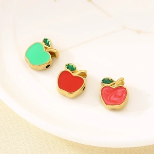 Macro shot of three colorful enamel apple charms in red, pink, and green for jewelry