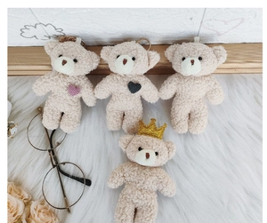 Detailed view of plush teddy bear keychains featuring heart embroidery and gold crowns