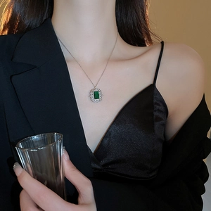 Primo piano di una collana in argento con pietra verde taglio smeraldo indossata da modella