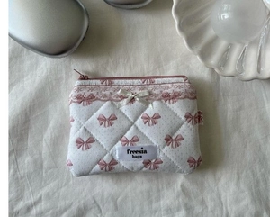 Detail of pink bow pattern quilted cosmetic bag with delicate lace trim and ribbon decor