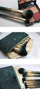 Detail of dark green shimmer makeup brushes with gold ferrule and matching glitter pouch