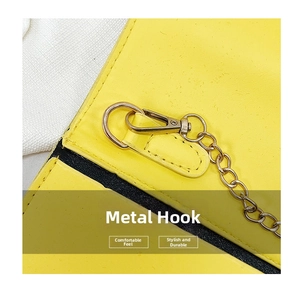 Macro shot of durable gold metal hook and fine chain links on a yellow crossbody bag