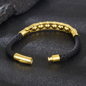 Close-up of golden stainless steel beads and black woven strap with magnetic clasp
