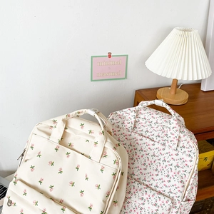 Close-up of floral canvas backpack featuring dual handles and side pockets on wooden desk