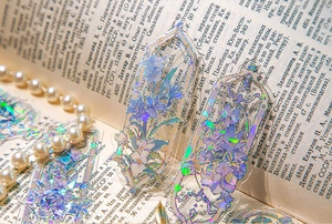Detail of PVC bookmark with purple lilies, embossed gold foil, and laser laser effect