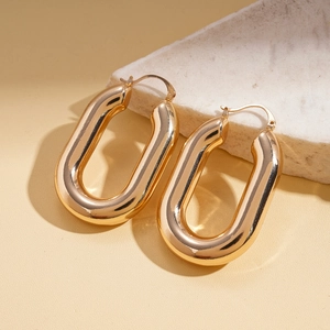 Macro view of thick gold U-shaped hoop earrings with a polished metallic finish