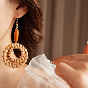 Détail de boucles d'oreilles bohèmes en rotin avec perle en bois sur mannequin