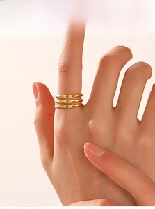 Close-up of a minimalist triple-layer gold stainless steel adjustable ring worn by a model