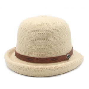 Detail of beige knitted cloche hat with a brown leather strap and decorative metal buckle