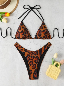 Flat lay of leopard print triangle bikini with sun hat and flowers for beach vacation