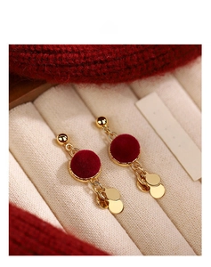 Close-up of red flocked round drop earrings with gold metal pendant on white jewelry box