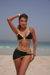 Detail view of black bikini with neon yellow and green trim on a sunny beach background
