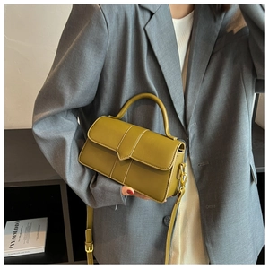 Olive green leather handbag with gold hardware shown on a grey blazer outfit