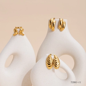 Three-pair set of 14K gold plated textured oval and knotted earrings on white vases