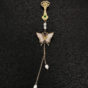 Détail de broche pompon de style chinois avec papillon doré, perles et gemme verte