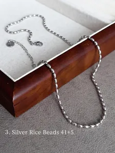 Detailed macro view of a silver rice bead chain necklace with adjustable extender link