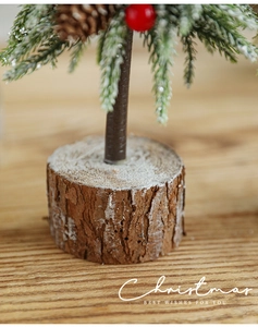 Close-up of natural wood base on 24cm mini snowy Christmas tree with red berries