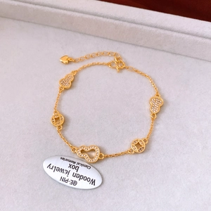 Détail de la gourmette dorée 24k avec gourde et pièce sur un plateau à bijoux