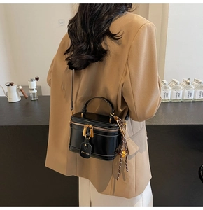Detail of black glossy leather box bag with gold zippers and metal logo hardware