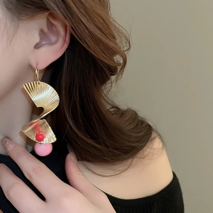Detail eines goldenen Spiralfächer-Ohrrings mit rosa Harzperle am Model