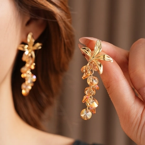 Detail of vintage flower tassel earrings with golden metal and orange crystal beads
