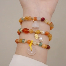 Close-up of layered beaded bracelets with pearls, lotus charms and green jade stones