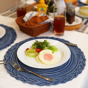 Blue round braided placemat on dining table with white plate and breakfast setting