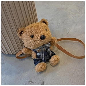 Detail of cute brown plush teddy bear bag featuring blue denim overalls and plaid bow