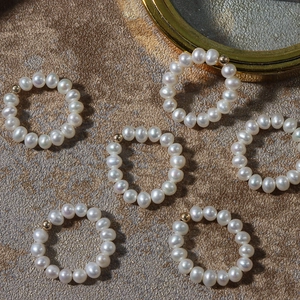 Handmade natural freshwater pearl rings with 14K gold filled beads on stone surface