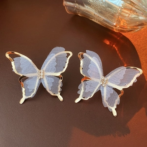 Detail of gold-plated butterfly earrings with delicate white lace wings and small zircon stones
