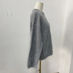 Dettaglio di un maglione grigio che mostra la trama in mohair a pelo lungo e morbidezza