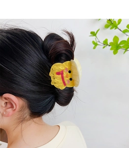 Close-up of a cute yellow cartoon chick acrylic hair clip worn on a model side profile