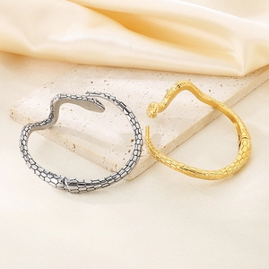 Detailansicht von Gold- und Silberschlangenarmbändern mit Schuppentextur auf Steinplatte