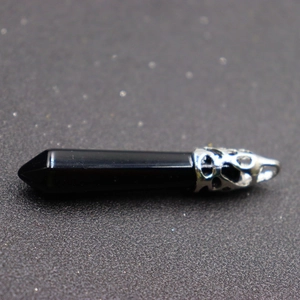 Macro shot of a black hexagonal stone pendant with a silver-tone filigree metal cap