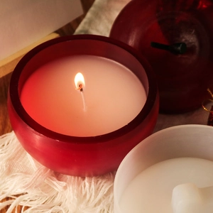 Scène chaleureuse d'un bougeoir rouge givré avec une flamme vacillante et lumière douce