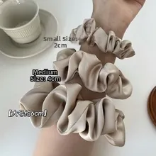 Three sizes of champagne silk scrunchies on wrist showing 2cm 4cm and 6cm widths