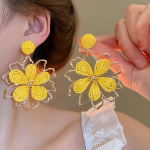 Close-up of a yellow woven raffia flower earring featuring a hollow metal frame for women