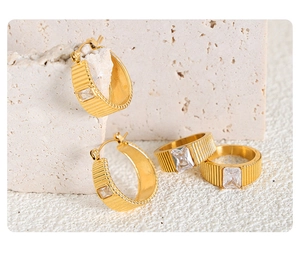 Dettaglio del set gioielli in acciaio al titanio dorato con texture e zircone quadrato