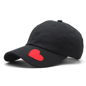 Dettaglio del ricamo a cuore rosso sul lato di un cappello da baseball in cotone nero