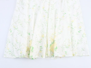 Close-up of white dress hem with yellow floral embroidery and eyelet lace fabric