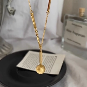 Elegant gold necklace with frosted ball pendant and bamboo-style chain on display