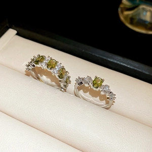 Macro shot of silver rings with oval olive green gemstones and white diamond accents