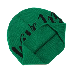 Detailed close-up of neon green knit beanie with black jacquard lettering and fold-over cuff