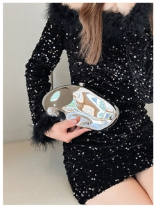 Close-up of metallic silver irregular clutch bag with spherical lock held by a model
