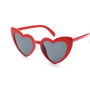 Detail view of stylish red heart-shaped party sunglasses with dark grey lenses