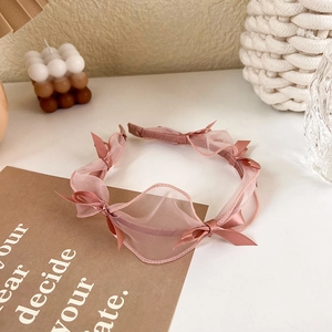 Detailed view of pink mesh lace headband with satin bow in a cozy setting