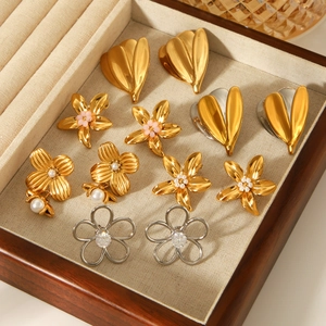 Gold and silver stainless steel flower earrings displayed in a wooden jewelry box