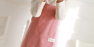 Detail of red and white striped cotton linen apron featuring a large pocket with a woven label