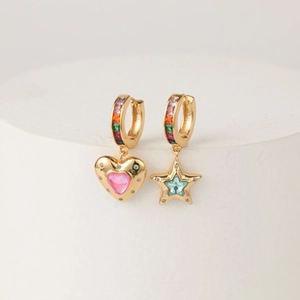 Detailed macro of gold-plated mismatched rainbow earrings with heart and star charms
