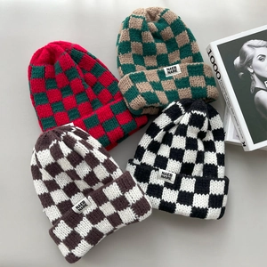 Detailed view of four checkered thick knit winter beanies in red, green, black and brown.